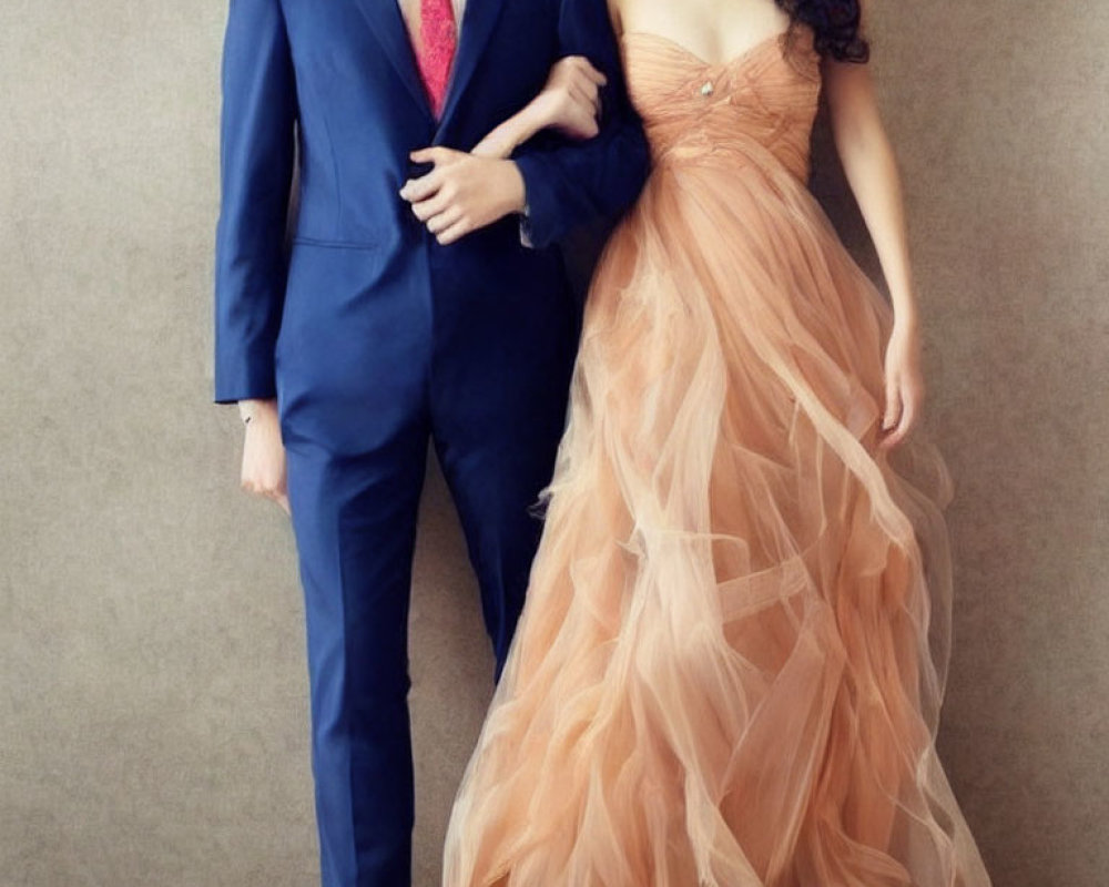 Man in Blue Suit and Woman in Peach Gown Posed Together