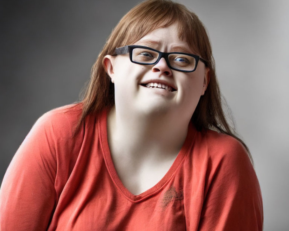 Smiling person with glasses in orange top on grey background