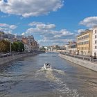 Historic city river scene with two boats under cloudy sky