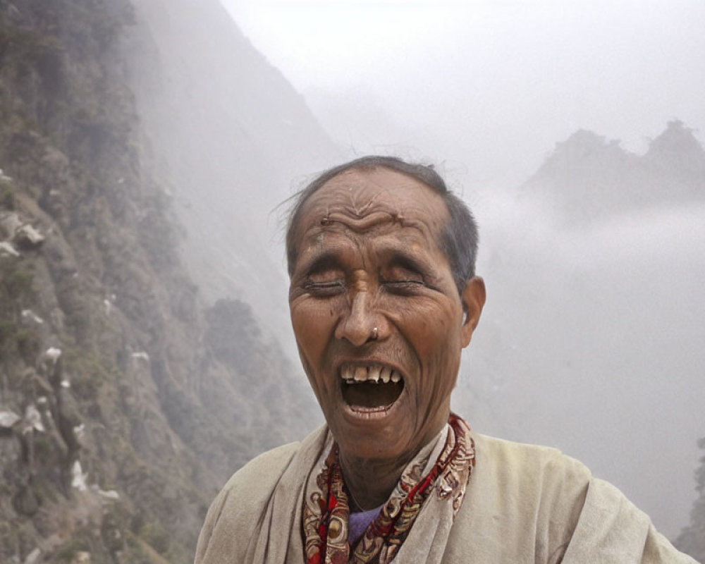 Elderly man smiling in front of misty mountains