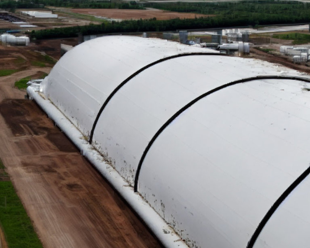 Large white industrial tent-like structures with curved roofs in aerial view.