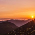 Colorful digital artwork of sunset over lake with mountains and trees.