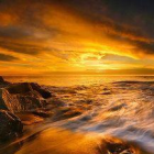 Golden sunset over serene icy landscape with snow reflecting warm light, silhouetting distant mountains against vibrant sky