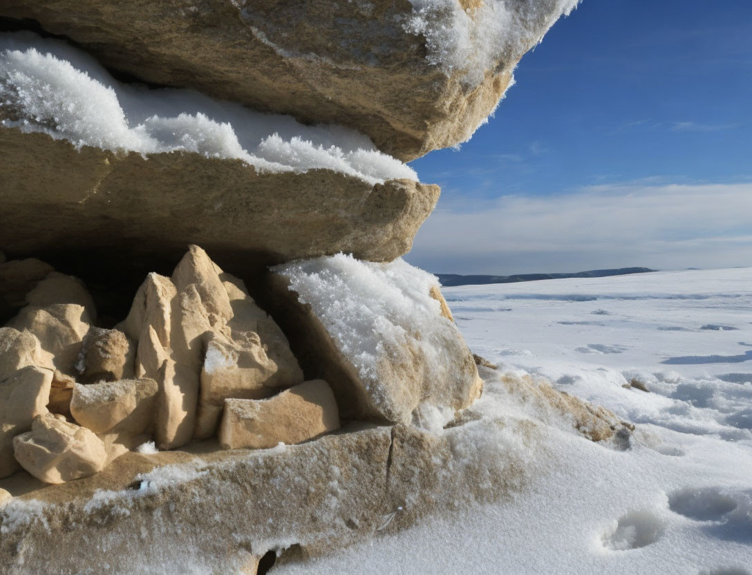 Snow-covered rocky outcrop in clear blue sky scene.