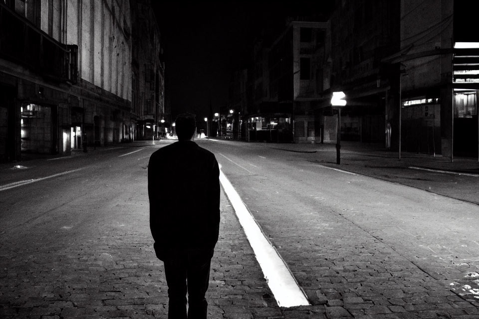 Solitary figure in deserted urban street at night