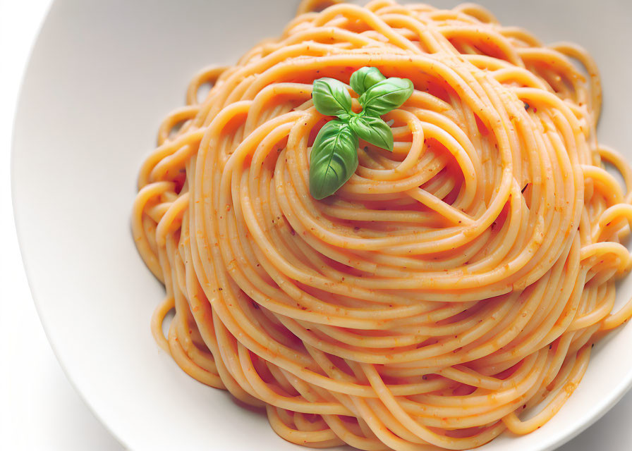 Plate of spaghetti with tomato sauce and basil garnish.