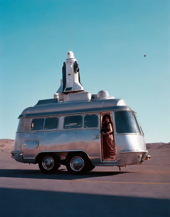 Vintage bus with space shuttle on top in desert landscape with person looking out