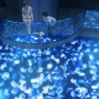 Artistic depiction of people viewing a blue jellyfish tank with a boat in a dark setting