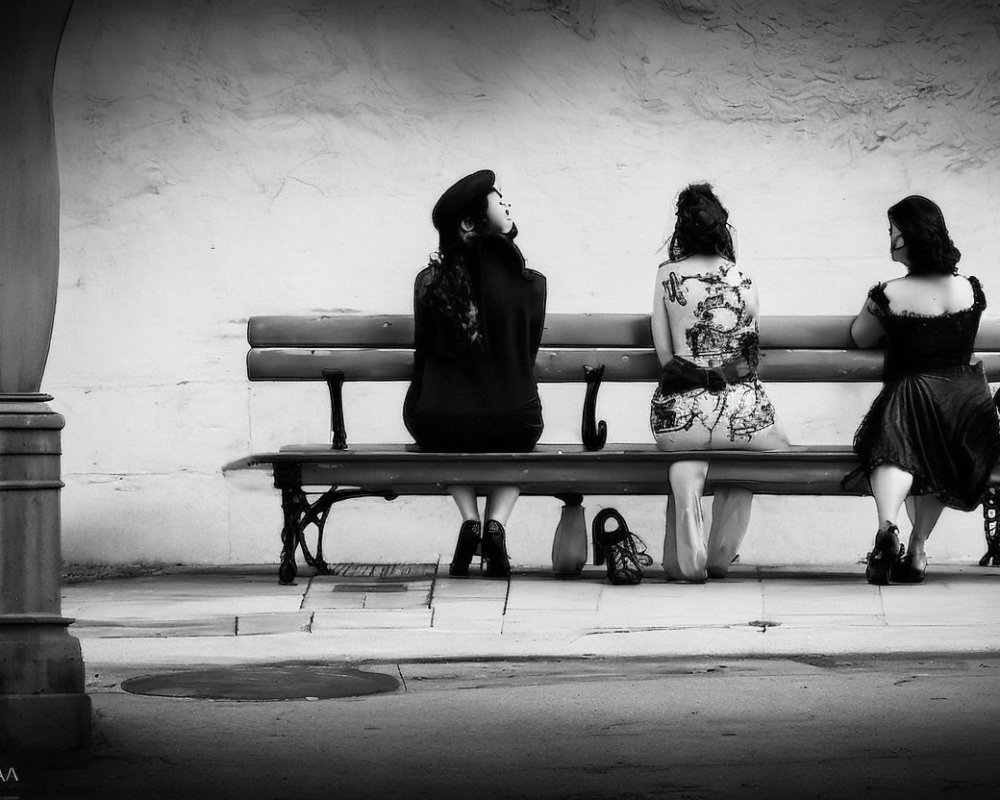 Three People Seated on Bench in Monochromatic Setting
