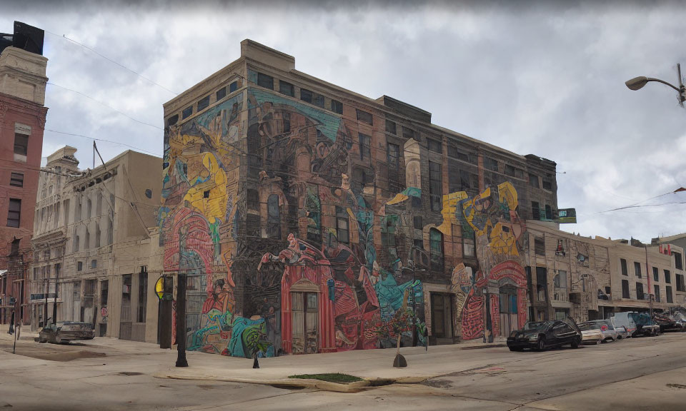 Urban street-corner building with vibrant mural under cloudy sky