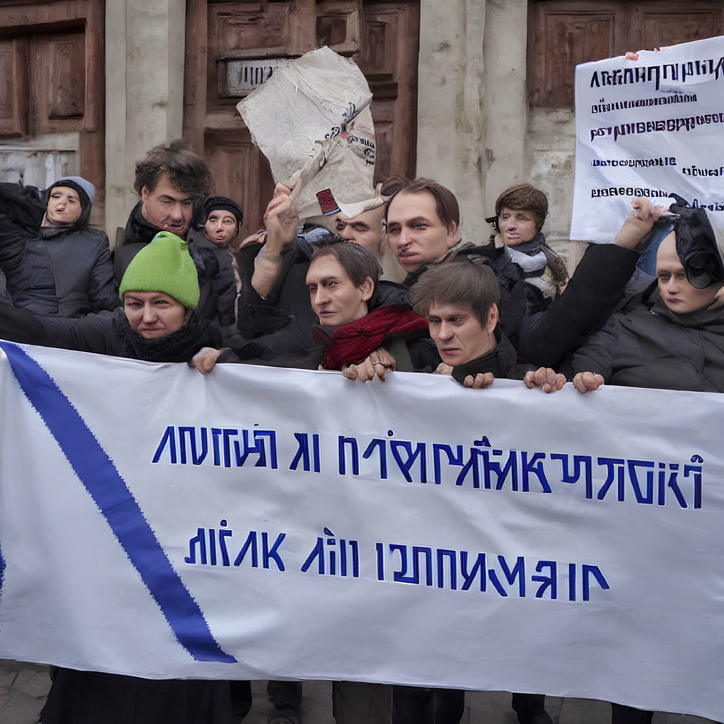 Public demonstration with banner and placards outside building