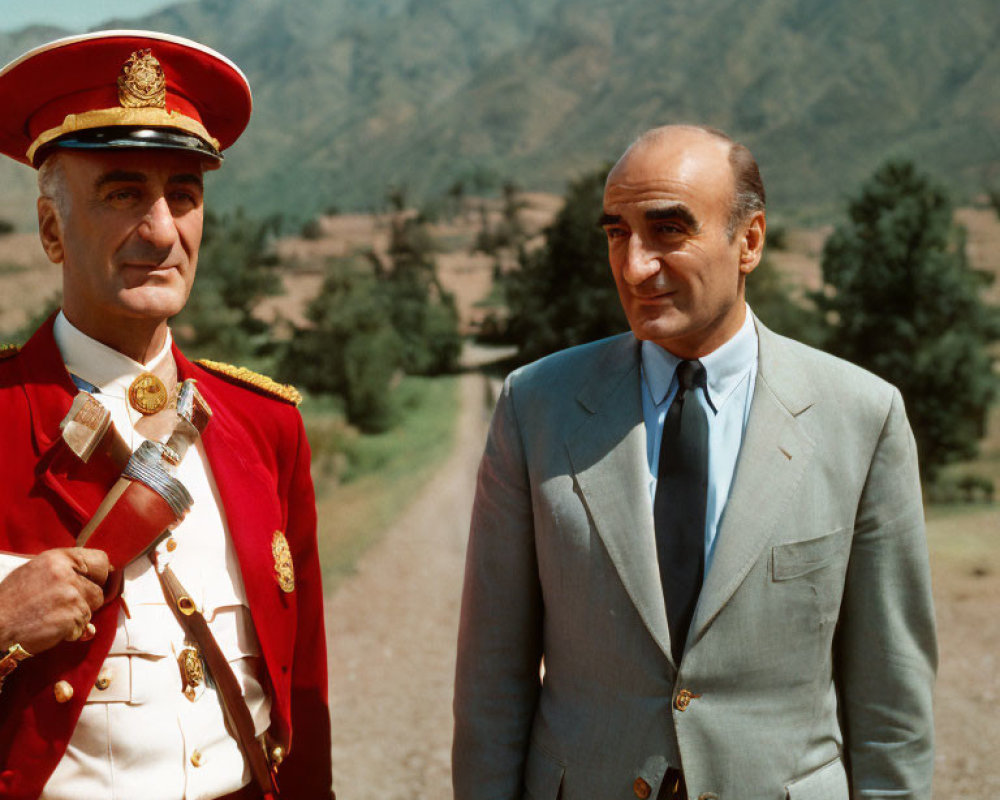 Men in red military uniform and gray suit outdoors.