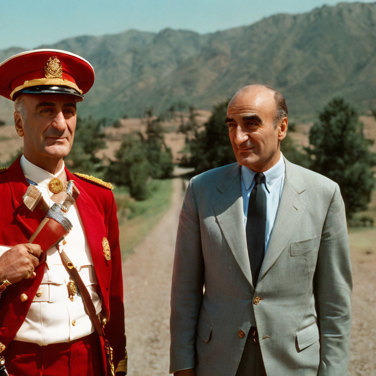 Men in red military uniform and gray suit outdoors.