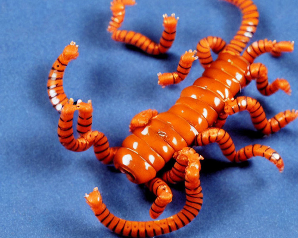 Orange Toy Scorpion with Articulated Limbs on Blue Background