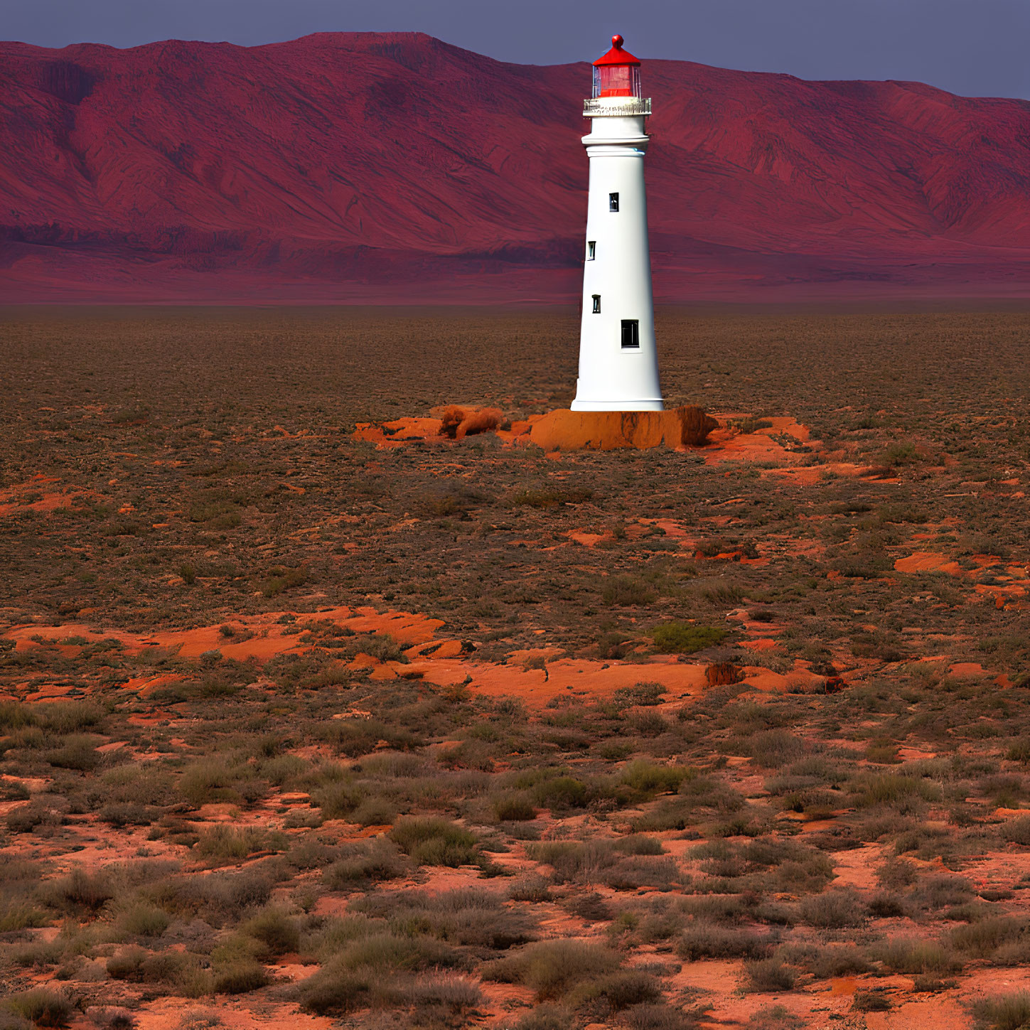 White Lighthouse with Red Top in Barren Desert Landscape