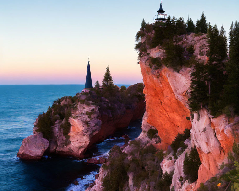 Lighthouse on rugged cliff at dusk overlooking ocean and trees.