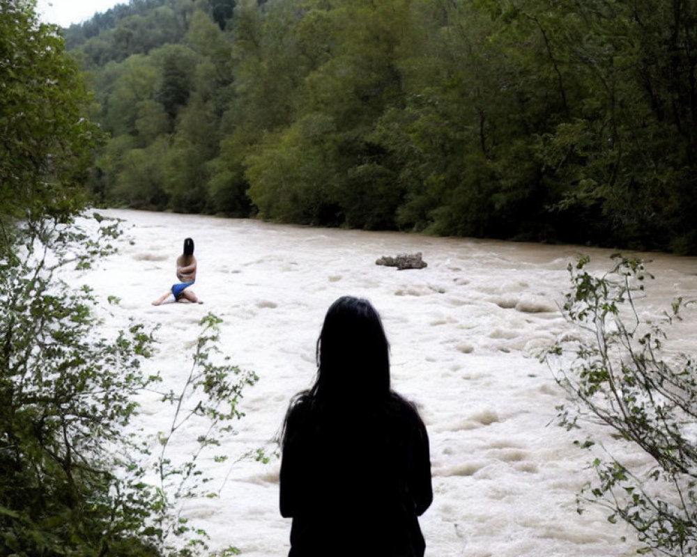 Two individuals in nature by a fast-flowing river surrounded by greenery