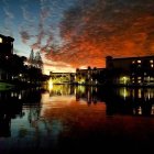 Scenic city river at sunset with orange clouds and illuminated buildings