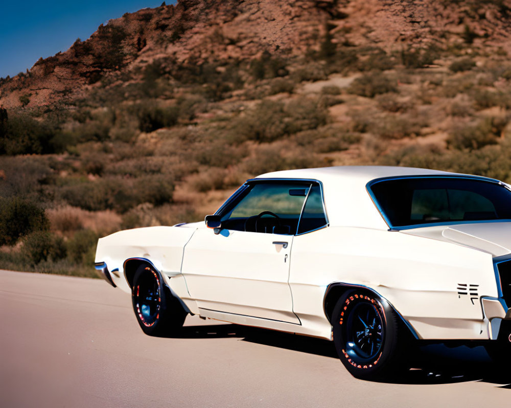 Vintage white car with black trim on road with rocky hill and blue sky