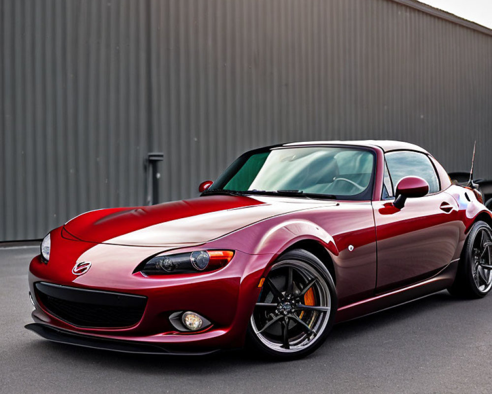 Red Sports Car with Black Rims Parked Outside Gray Industrial Building