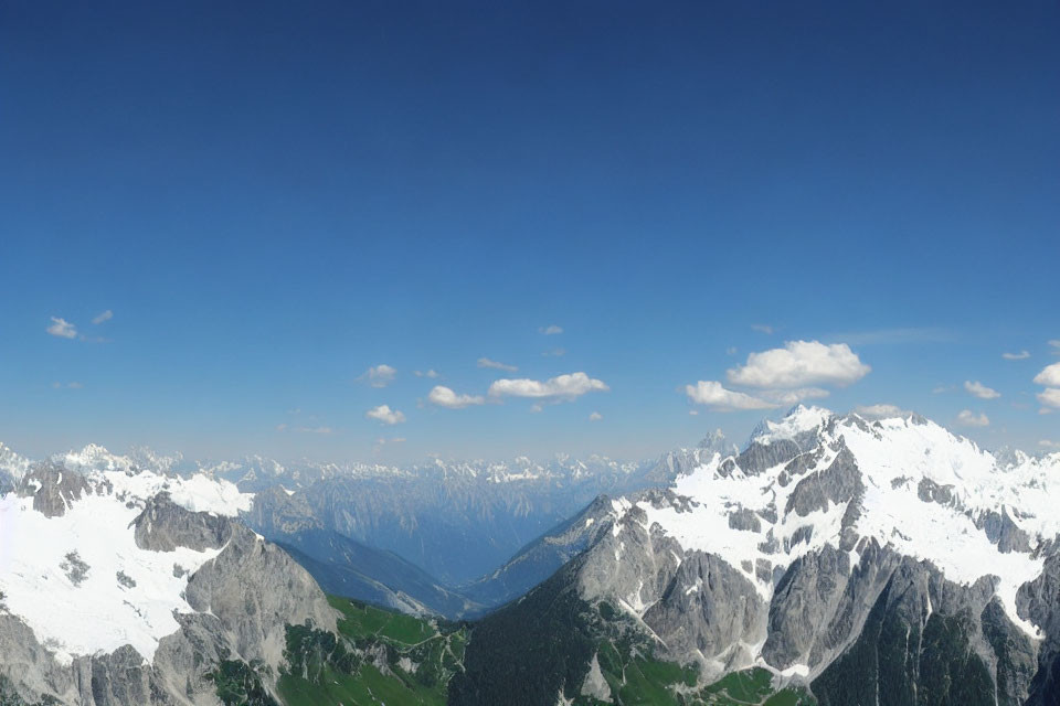 Snow-capped mountains and green valleys under clear blue sky