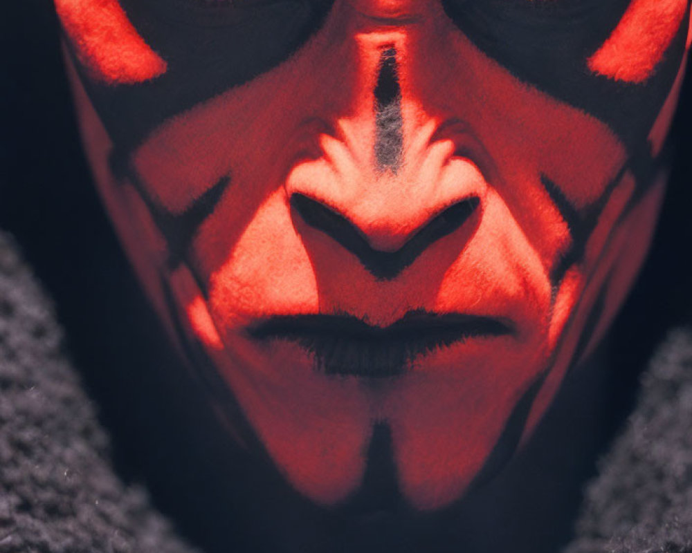 Intense red and black face paint on person with striking eyes