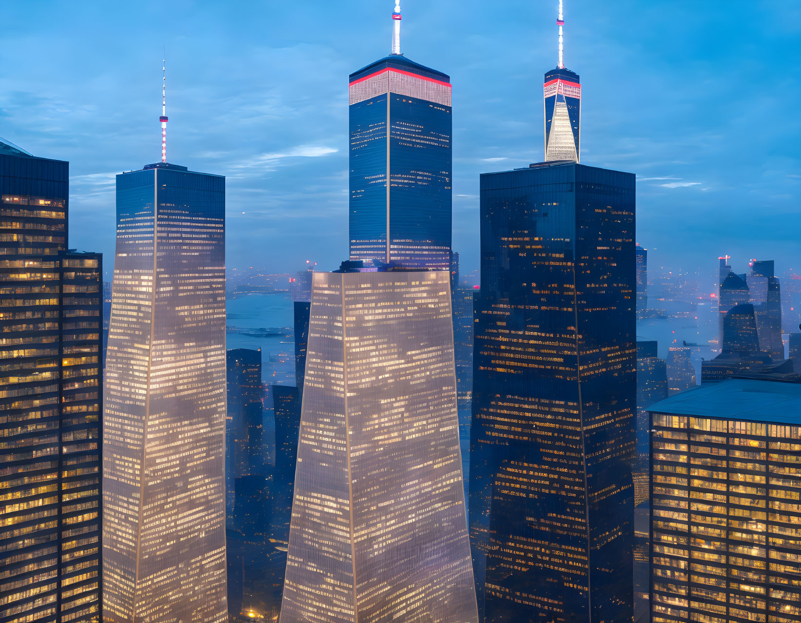 Dusk skyline with illuminated skyscrapers against dusky blue sky