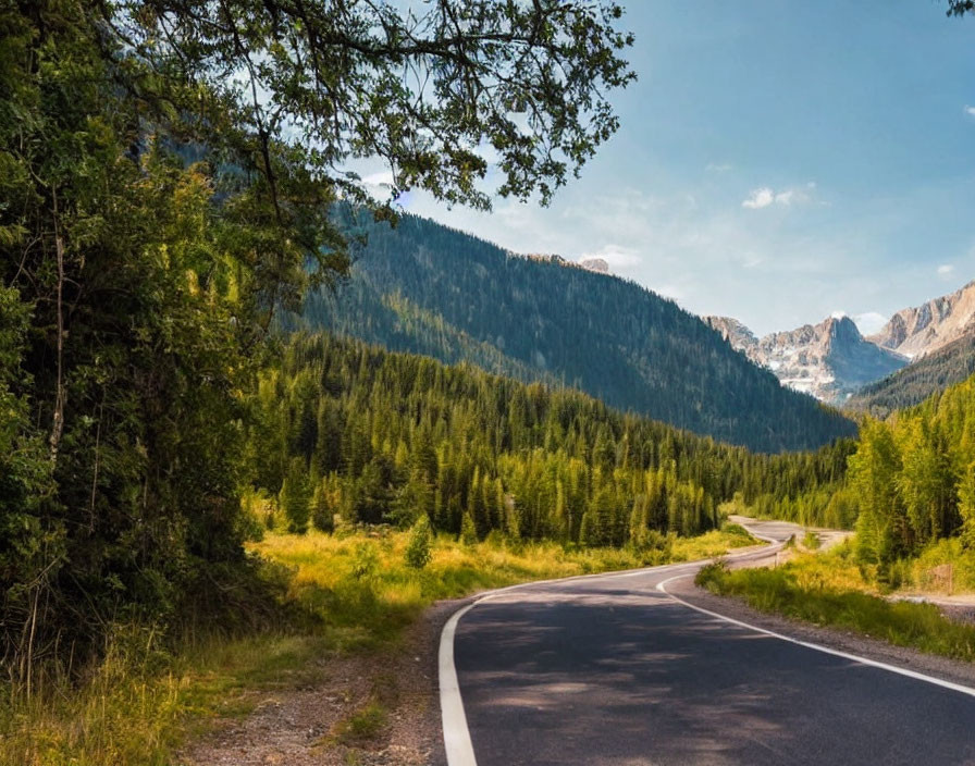 Scenic image of winding road in lush forest with mountains under clear sky