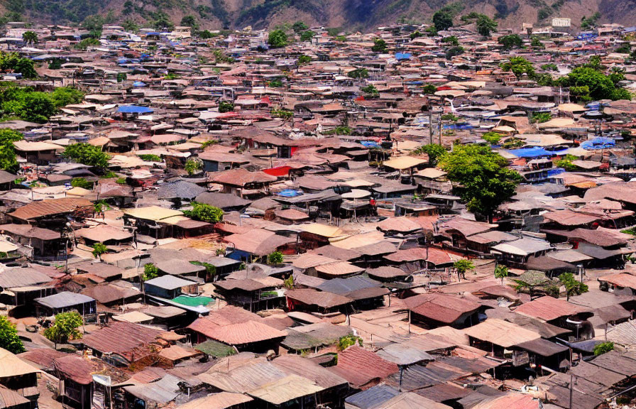 Cluster of makeshift houses with corrugated metal roofs in hilly area.
