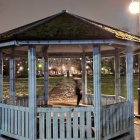 Ornate gazebo by pond under starry sky with street lamps