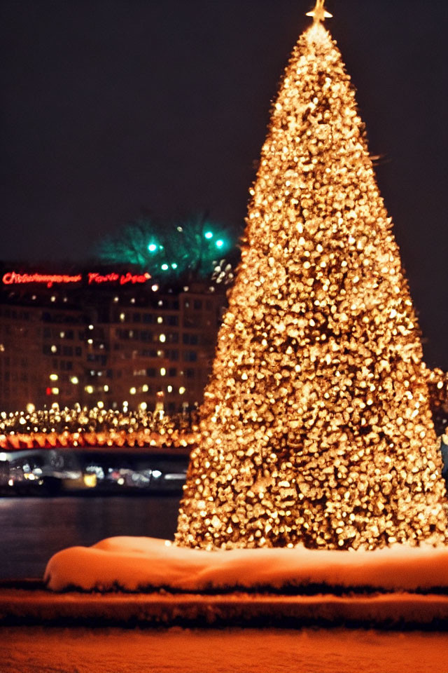 Snowy Christmas tree with golden lights against night cityscape