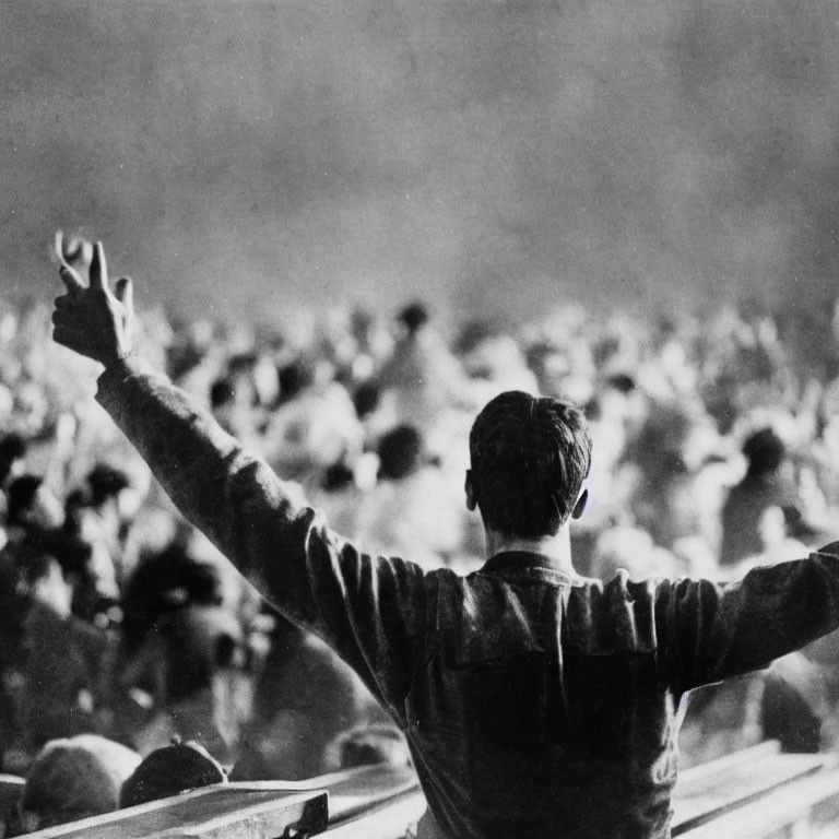 Person making victory sign to blurred crowd in background