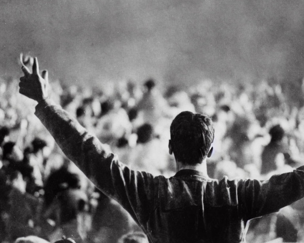 Person making victory sign to blurred crowd in background