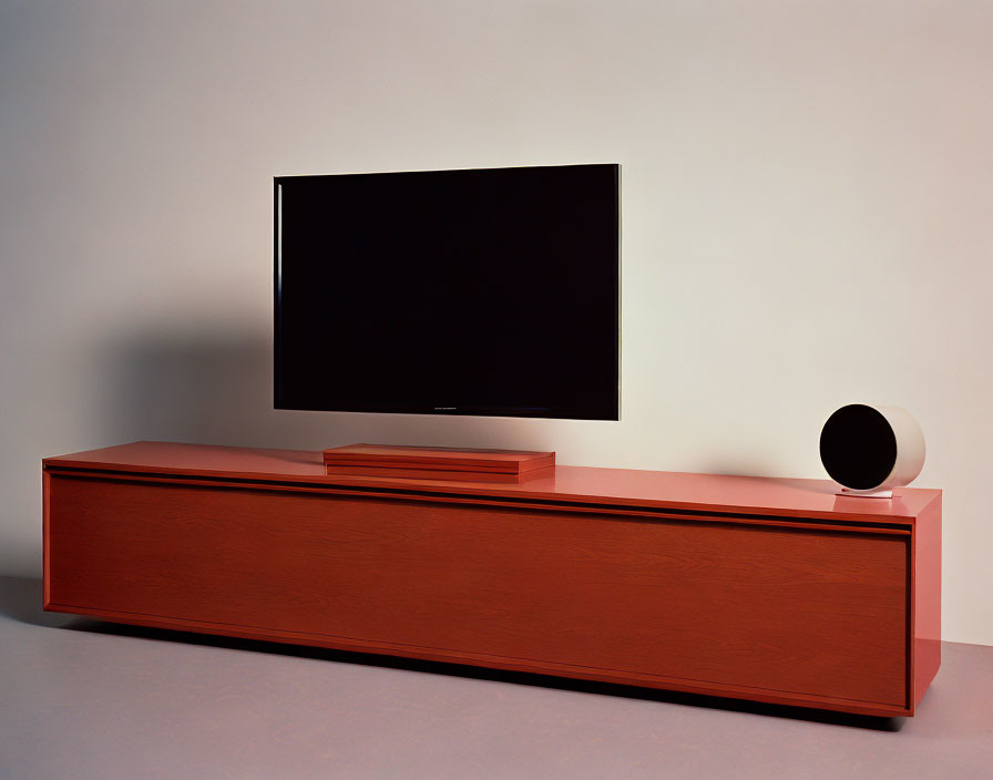 Contemporary living room with flat-screen TV, wooden console, and spherical speaker on neutral background