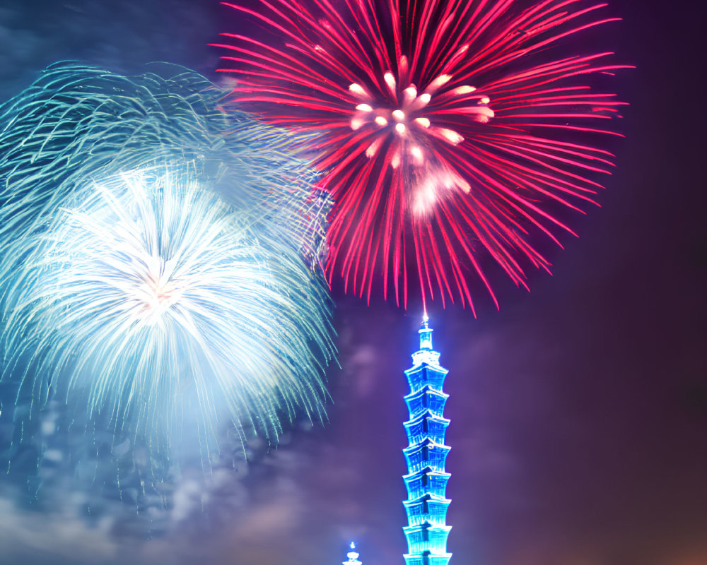 Colorful fireworks illuminate night sky above lit skyscraper