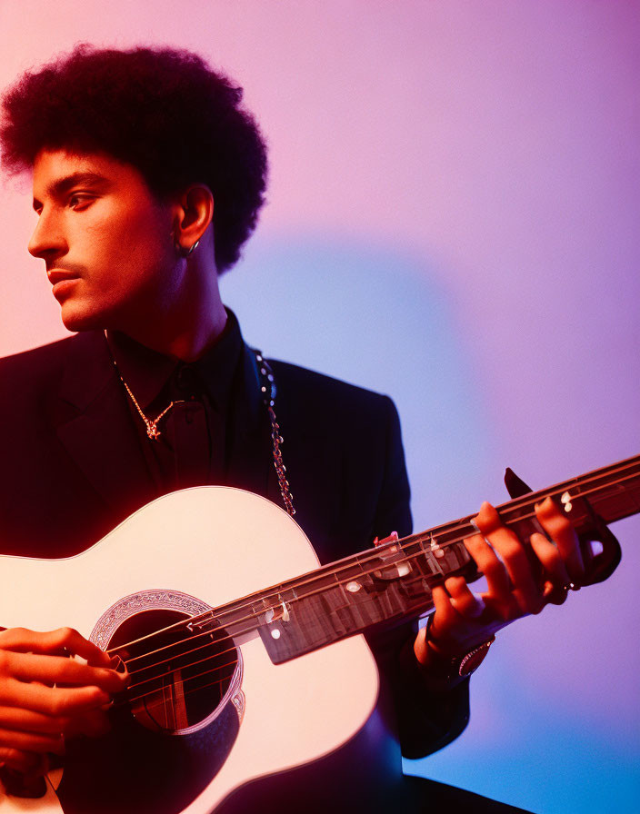 Person with Afro Playing Acoustic Guitar in Pink and Purple Lighting