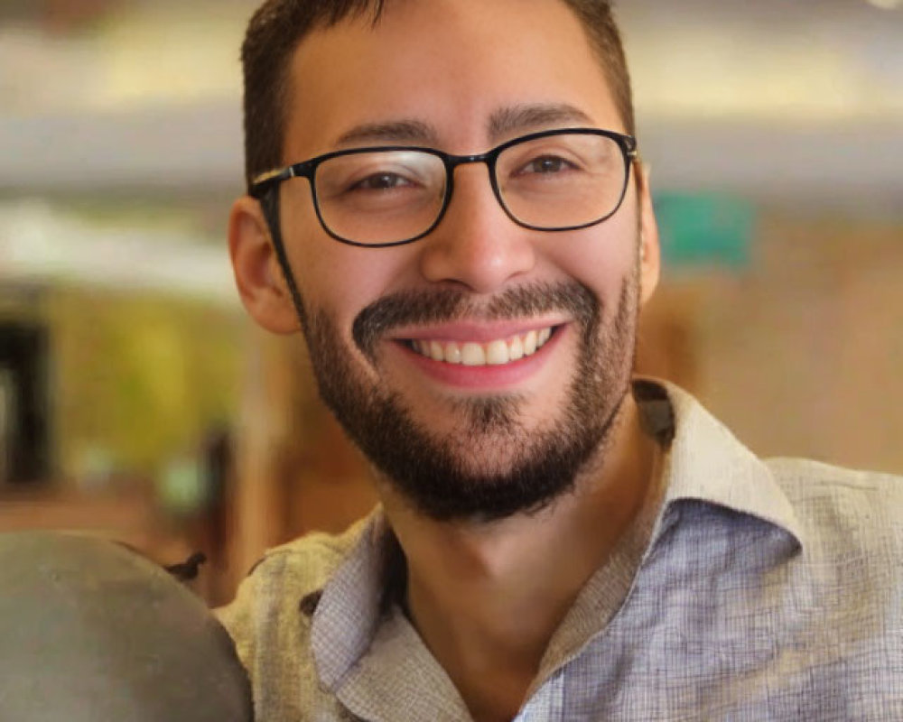 Smiling man with glasses in gray shirt indoors