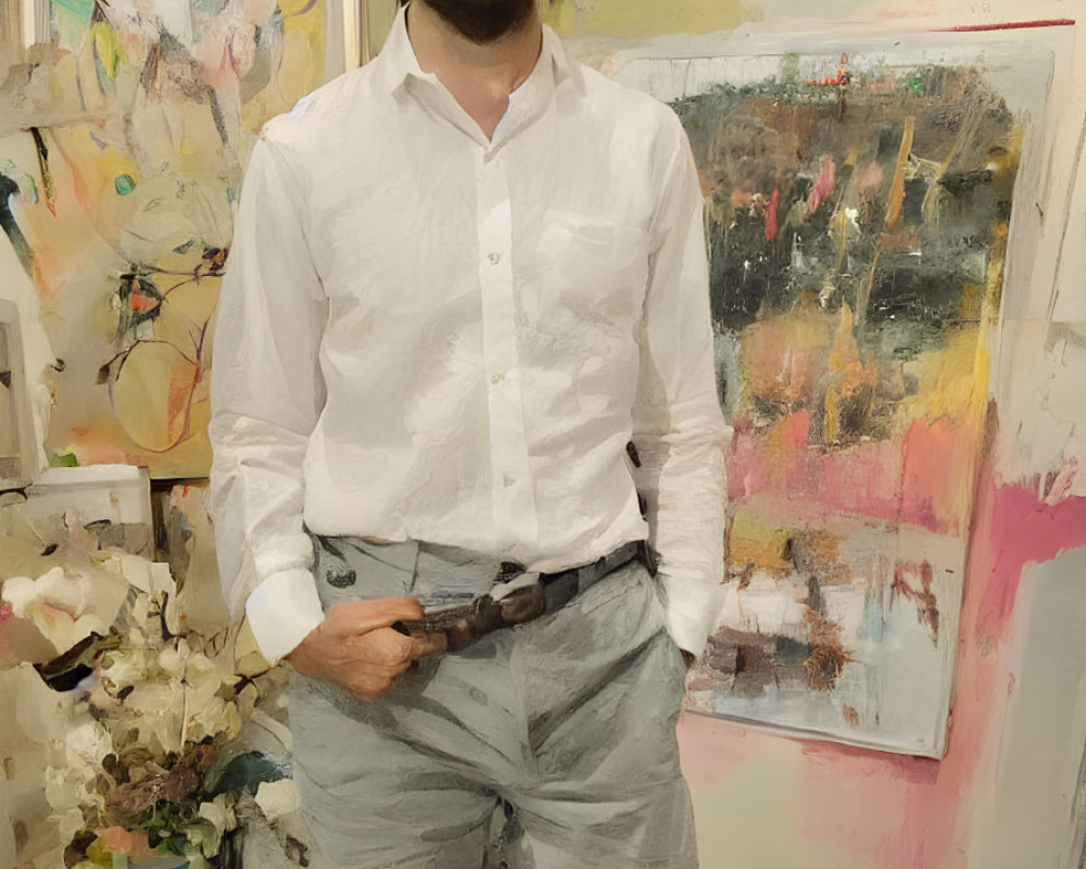 Man in white shirt and grey pants in art studio with colorful abstract paintings