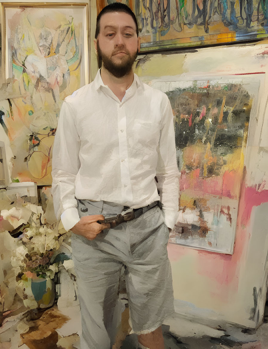 Man in white shirt and grey pants in art studio with colorful abstract paintings