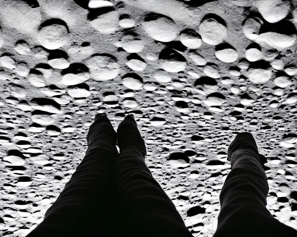 Monochrome image of legs on pebbled surface with dramatic lighting