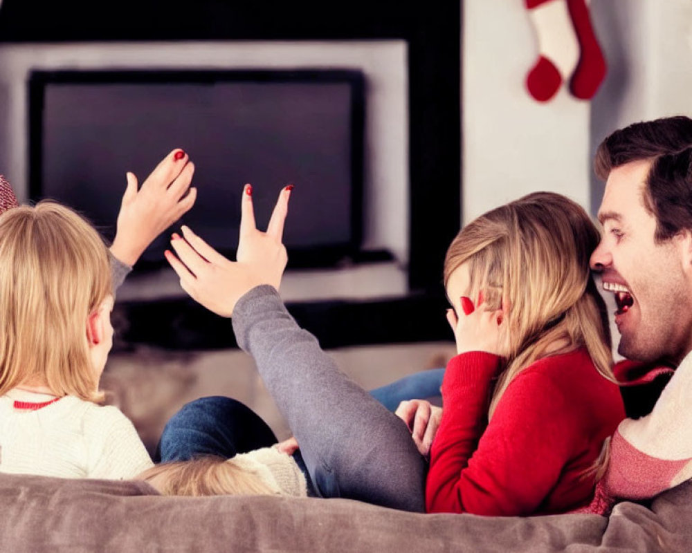 Family laughing on couch in Christmas decorated room with blank screen TV