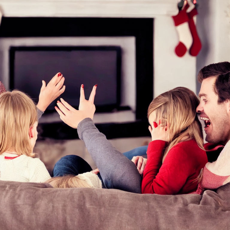 Family laughing on couch in Christmas decorated room with blank screen TV