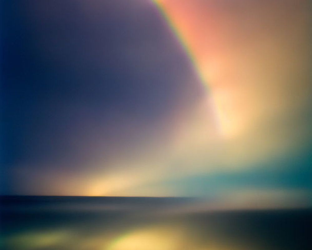 Vibrant rainbow over calm sea at sunset