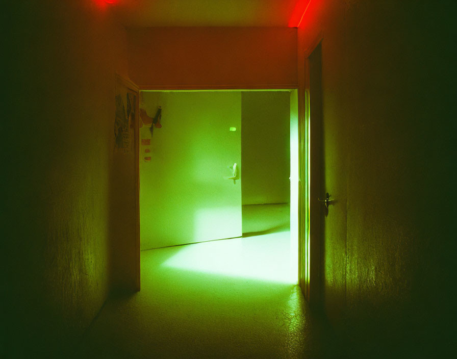 Dimly Lit Corridor with Green and Red Lighting Leading to Bright Green Door