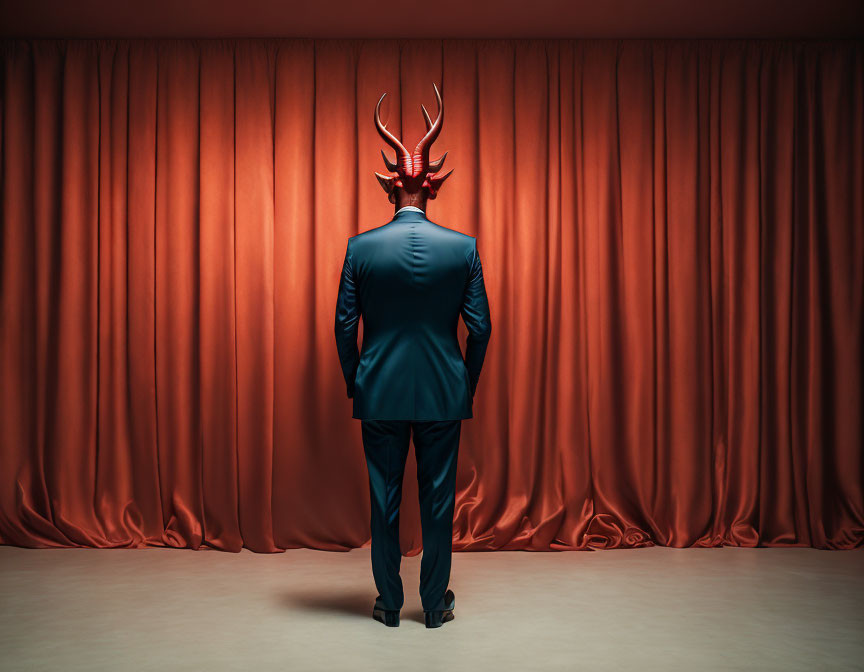 Person in Suit with Antlered Mask Standing in Front of Red Curtain