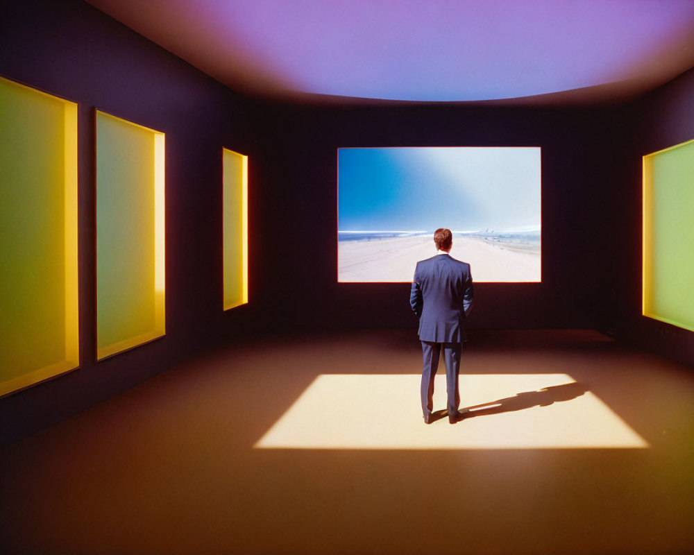 Man in suit in room with colorful frames, facing beach scene on screen