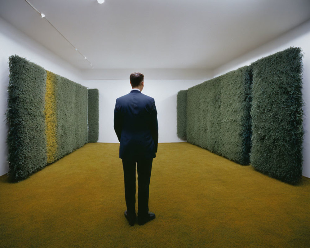 Man in dark suit in art gallery with green grass-like walls and yellow-green floor