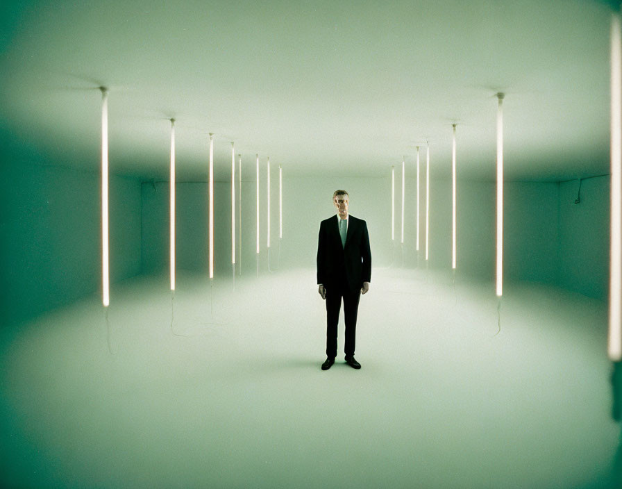 Symmetrical room with man in suit and vertical lights on greenish walls