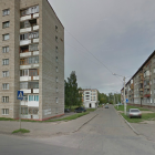 Abandoned urban crossroads with rundown buildings, lone tree, and classic car