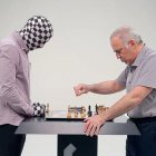 Cloaked Figures Playing Chess on Beach with Cloudy Sky